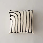 Coussin blanc avec des motifs noirs et blancs géométriques.
