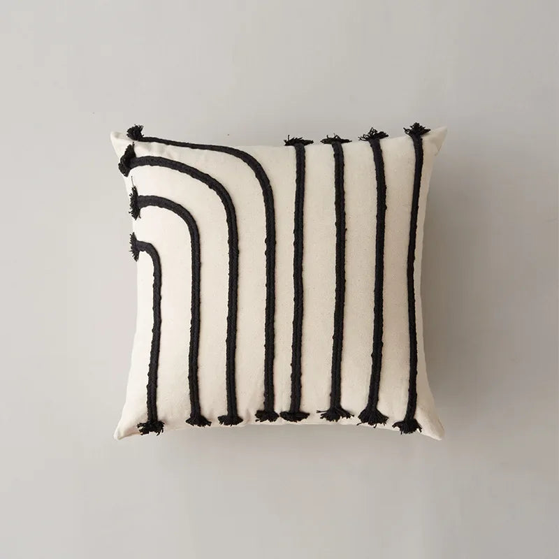 Coussin blanc avec des motifs noirs et blancs géométriques.