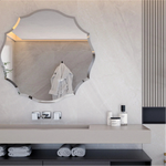 Un miroir décoratif dans une salle de bain moderne avec des accessoires de bain, une plante verte et un éclairage subtil.