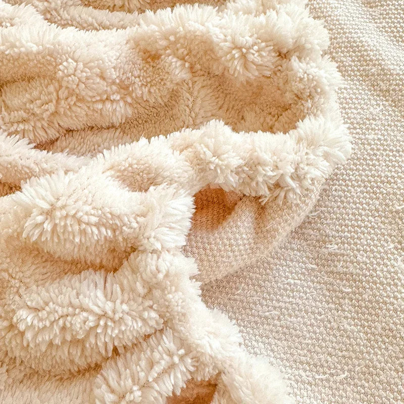 L'image montre un gros plan d'un tapis texturé doux et moelleux, composé de fibres beiges et blanches entrelacées, créant un motif organique et douillet.