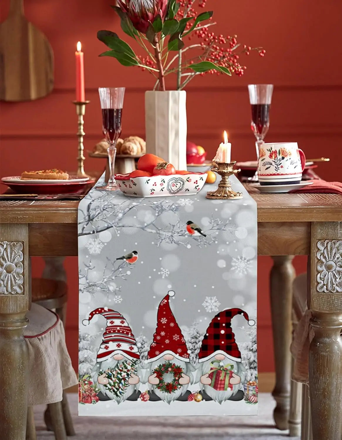 Le centre de table est orné de figurines gnomes dans des tenues hivernales colorées, avec des motifs de flocons de neige et d'oiseaux, sur un fond gris pâle, créant une ambiance festive et chaleureuse.