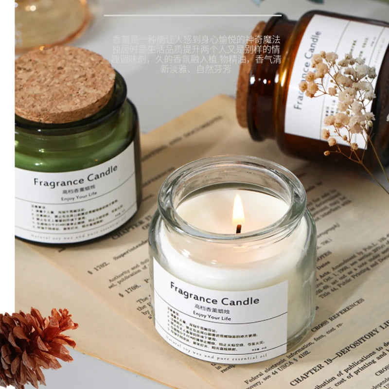 Voici une image de belles bougies parfumées posées sur un livre ouvert, accompagnées d'autres éléments de décoration comme une fleur séchée. L'éclairage doux crée une ambiance chaleureuse et intime.