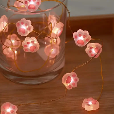 Guirlande lumineuse suspendue en forme de patte de chat rose allumée dans une chambre
