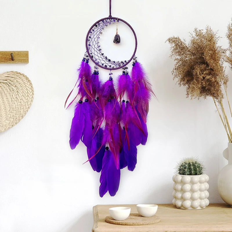 Un magnifique attrape-rêves violet suspendu, orné de plumes aux teintes profondes et colorées, créant une décoration murale élégante et bohème.