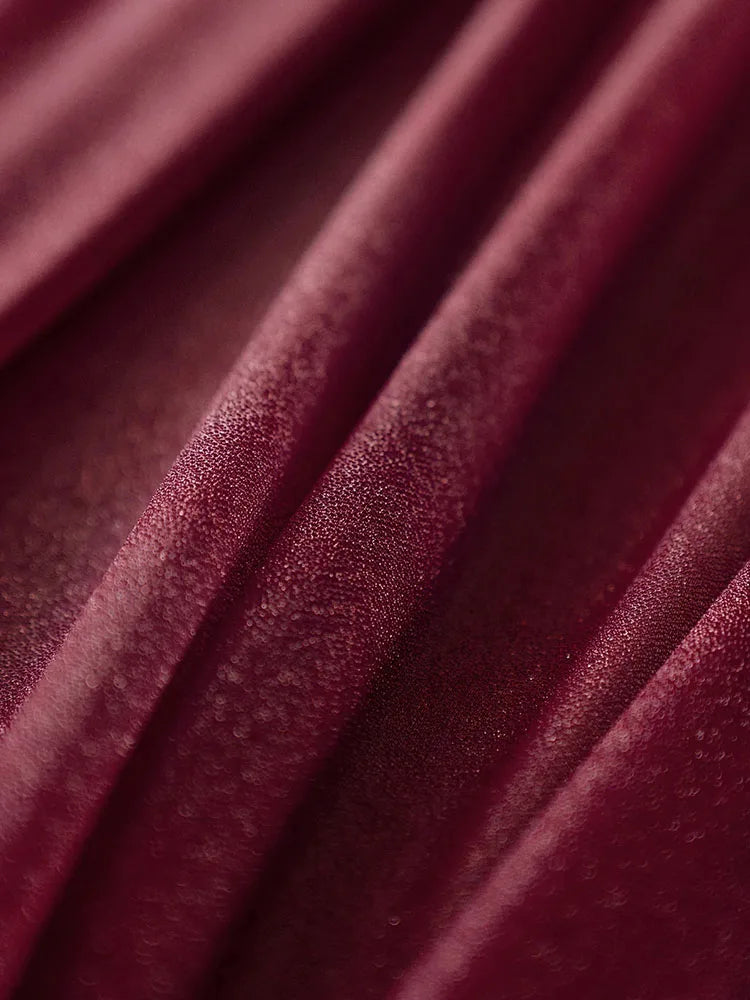 Riche et luxueuse texture de velours bordeaux avec des plis élégants.
