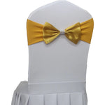 Une chaise blanche élégante avec un nœud papillon doré et décoratif, parfaite pour une occasion festive.