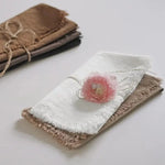 Un étui en tissu délicat et une fleur rose sur un fond clair.