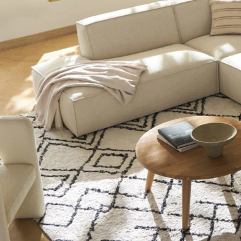 canapé d'angle moderne beige clair uni confortable salon minimaliste inclusion coussins tapis