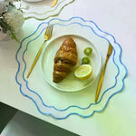 serviette table moderne blanc bleu clair bordure fine bords ondulés assiettes fourchettes dorées salade