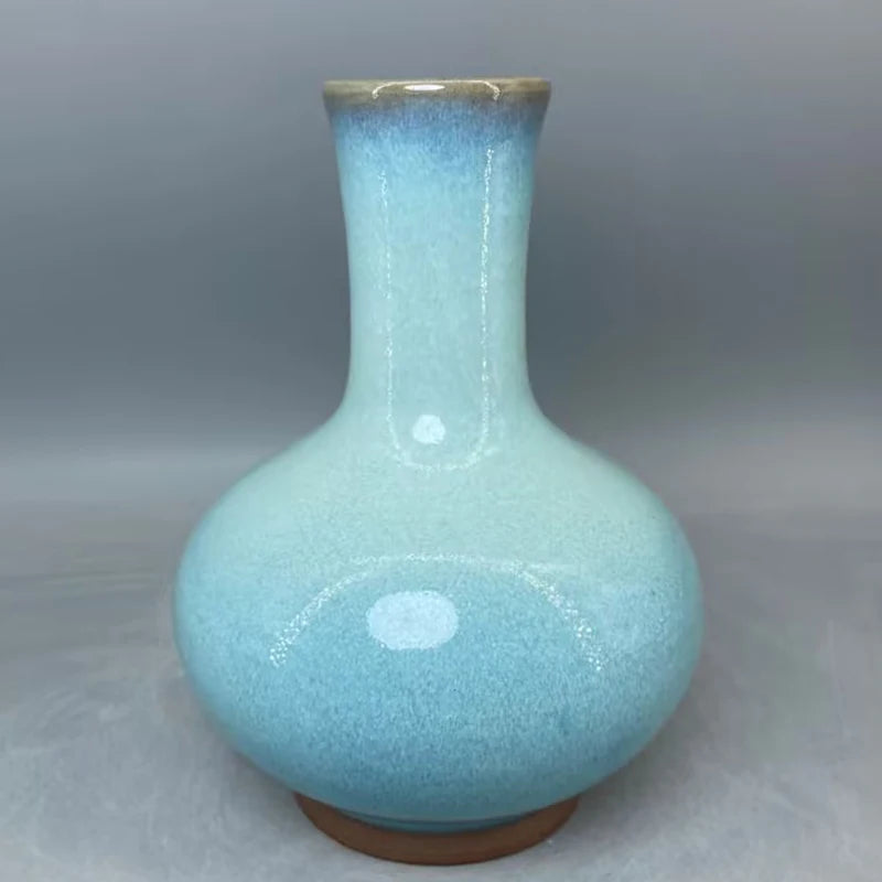 Un vase en céramique de couleur bleu clair aux formes élégantes et épurées, possédant un corps galbé et un col étroit, reflétant une esthétique raffinée et minimaliste.