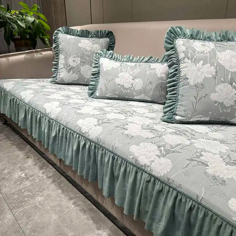 Ensemble de literie décoratif avec motif floral gris clair et vert menthe sur un canapé en peluche.