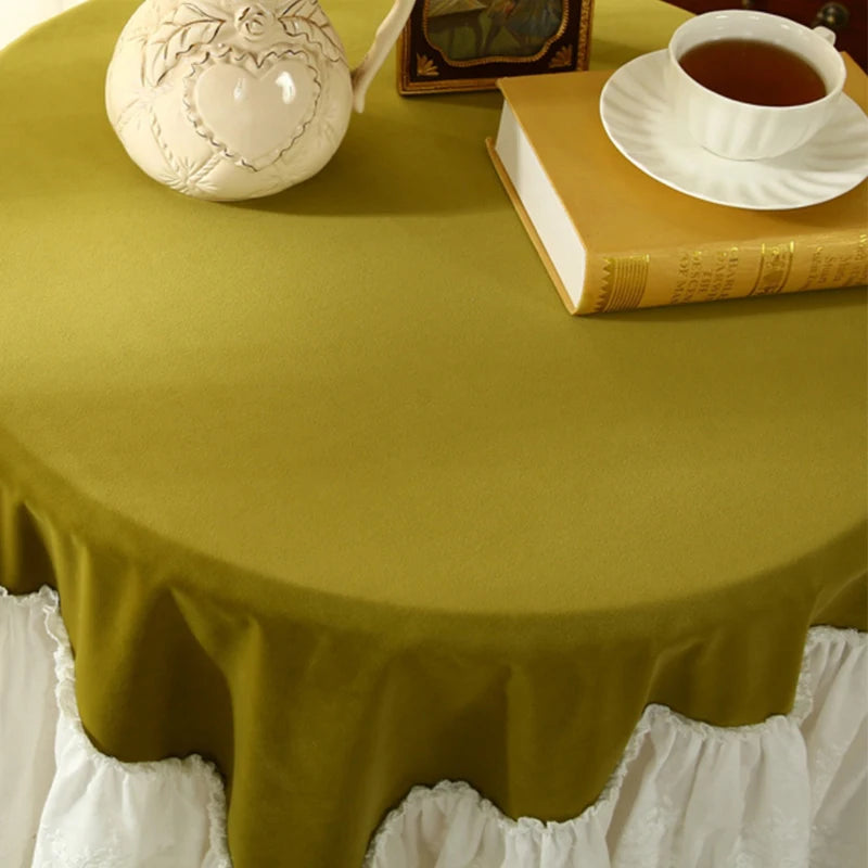 Une table ronde couverte d'une nappe jaune vif, ornée d'une jolie théière blanche et d'une tasse de thé, avec un livre posé sur le côté.