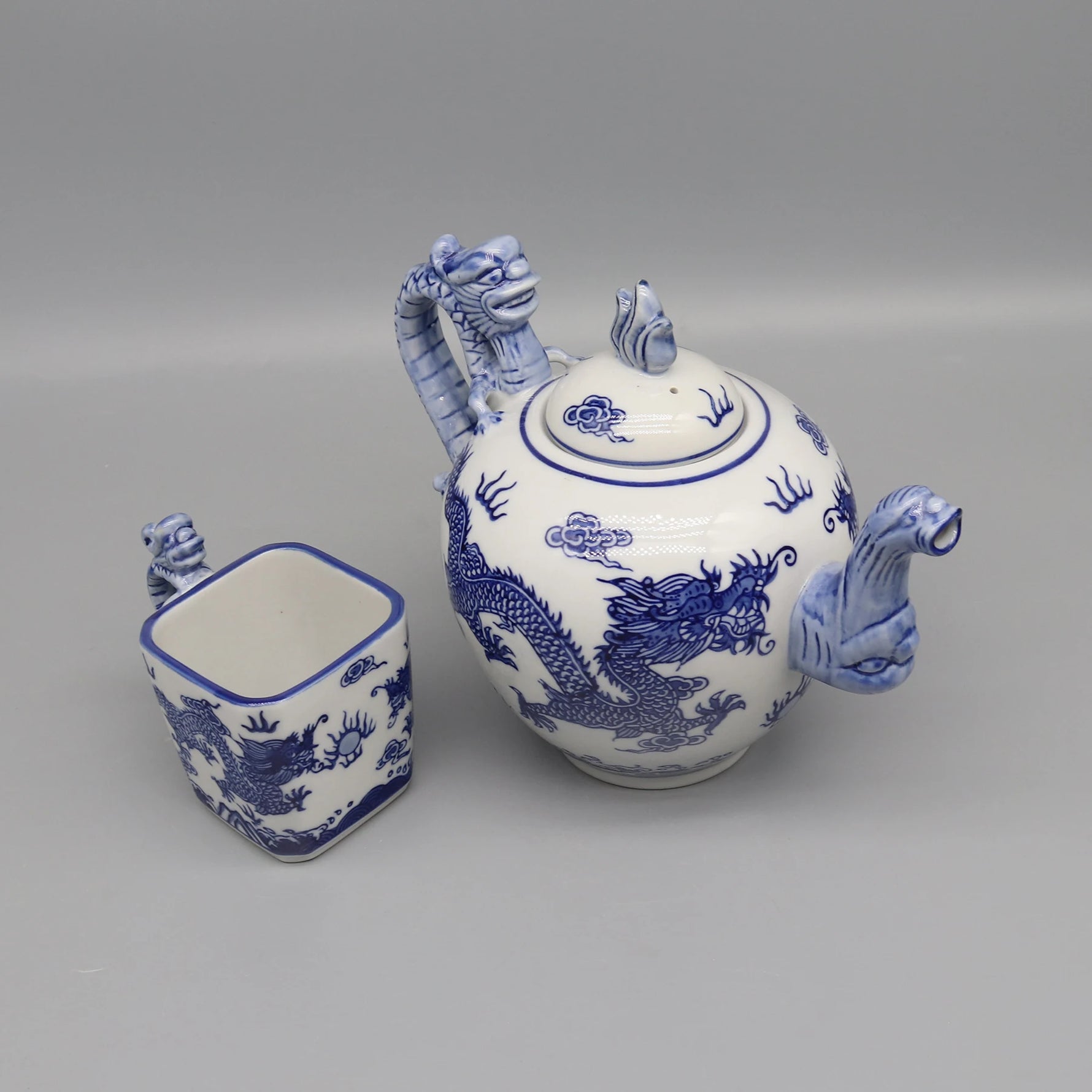 Pot à thé et tasse en céramique blanche et bleue décorés de motifs de dragons, reflétant la tradition et l'élégance de la culture chinoise.