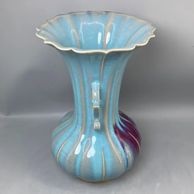 Un vase en céramique de forme élégante et aux couleurs turquoise et bordeaux, créant un design unique et artistique.