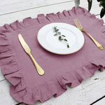 Une élégante vaisselle avec des couverts dorés posée sur un napperon de lin violet, offrant une présentation sophistiquée et raffinée pour une table.