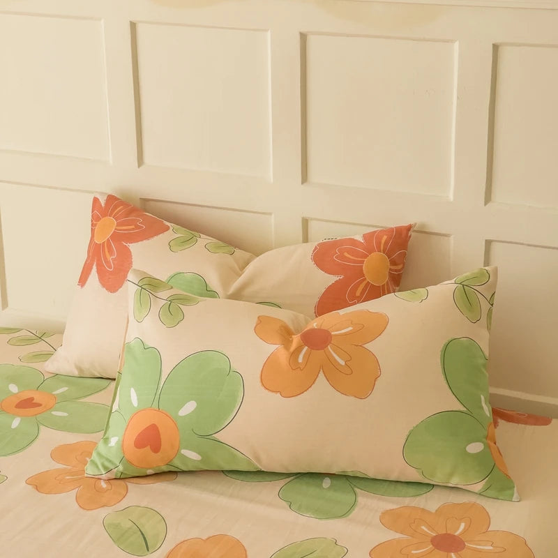 Coussins de lit décoratifs avec de grands motifs de fleurs colorées orange, vertes et beiges, sur un fond beige, créant une ambiance chaleureuse et charmante dans la chambre.