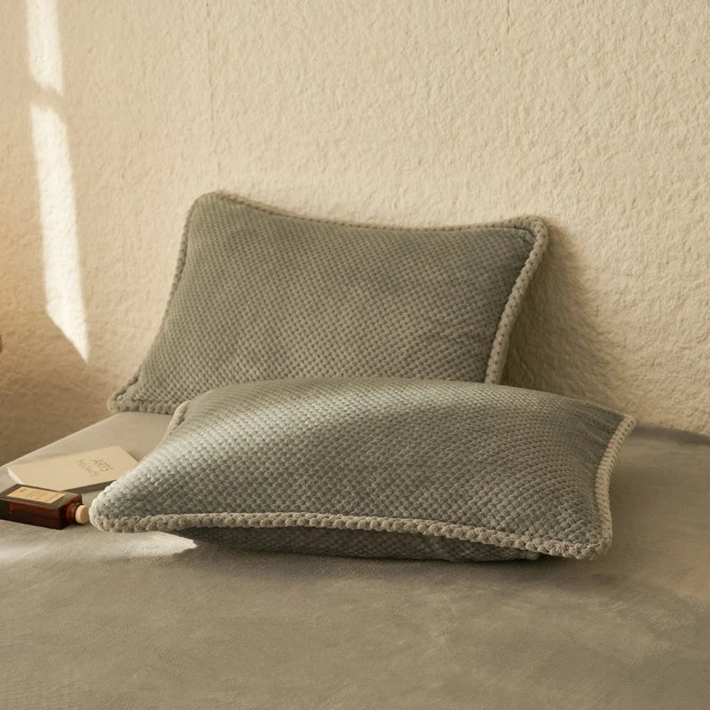 Deux coussins gris moelleux reposent sur une surface grise, créant une atmosphère confortable et relaxante.