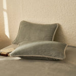 Deux coussins gris moelleux reposent sur une surface grise, créant une atmosphère confortable et relaxante.