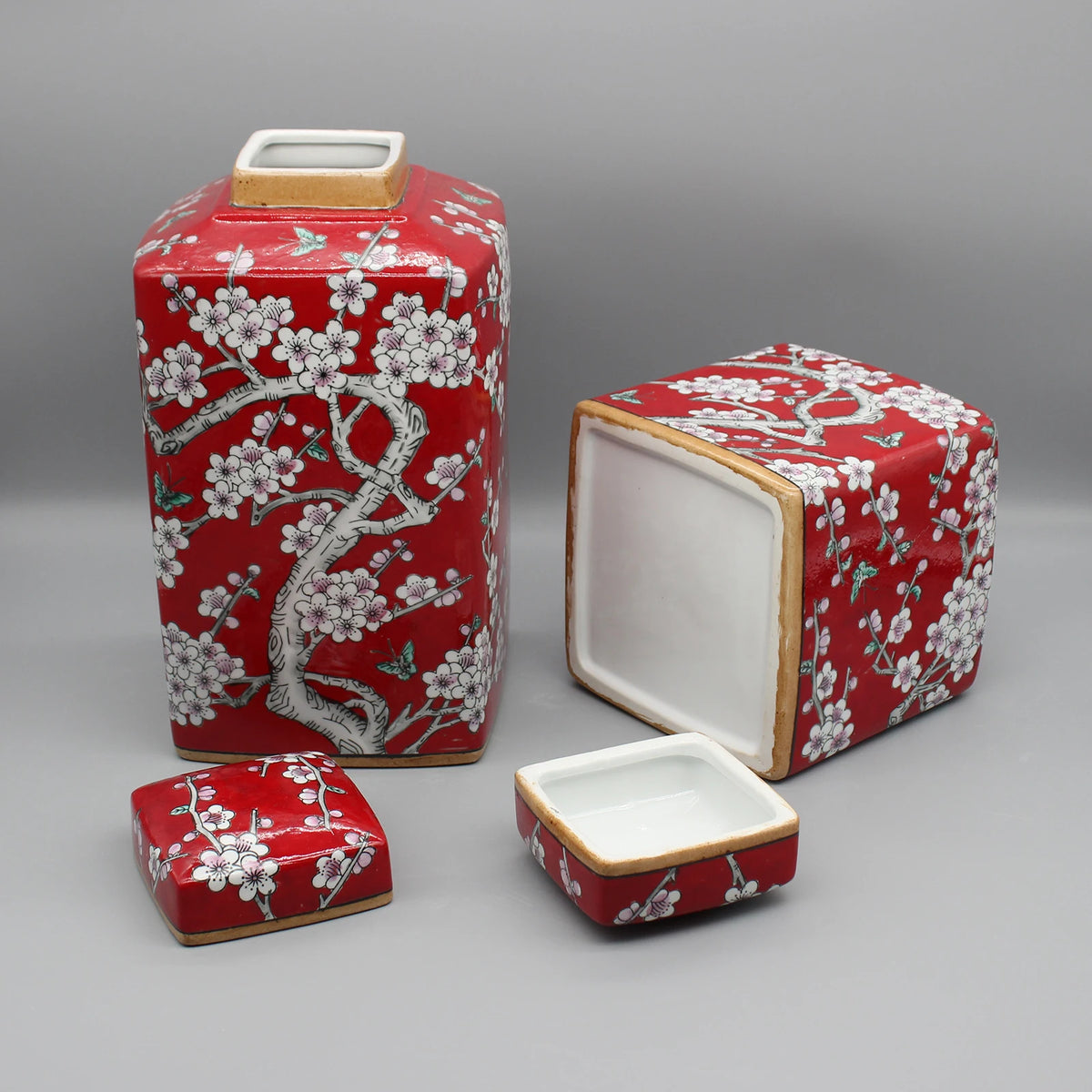 Des boîtes décoratives rouges et blanches avec des motifs floraux délicats.