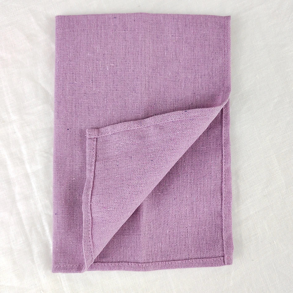 Une serviette lavande en coton tressé, aux motifs simples et épurés, offrant une texture douce et absorbante.