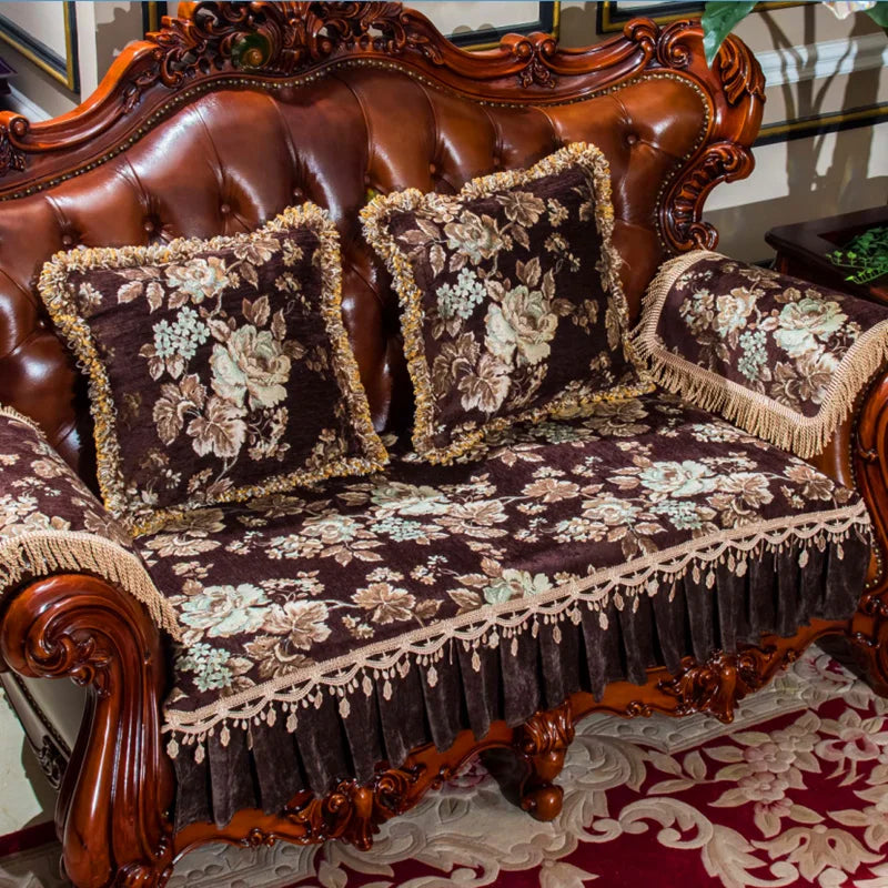 Un canapé en cuir brun richement orné de coussins et d'un couvre-lit brodé de motifs floraux élégants, créant une atmosphère de luxe et de sophistication dans la pièce.