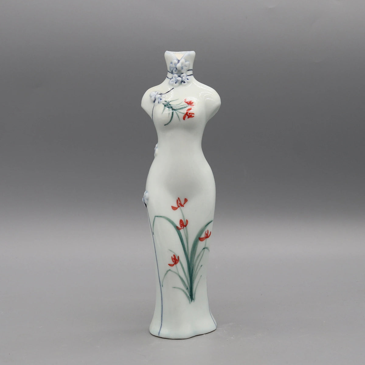 Vase délicat en porcelaine peint de délicates fleurs rouges et bleues, présentant une silhouette élégante et épurée.