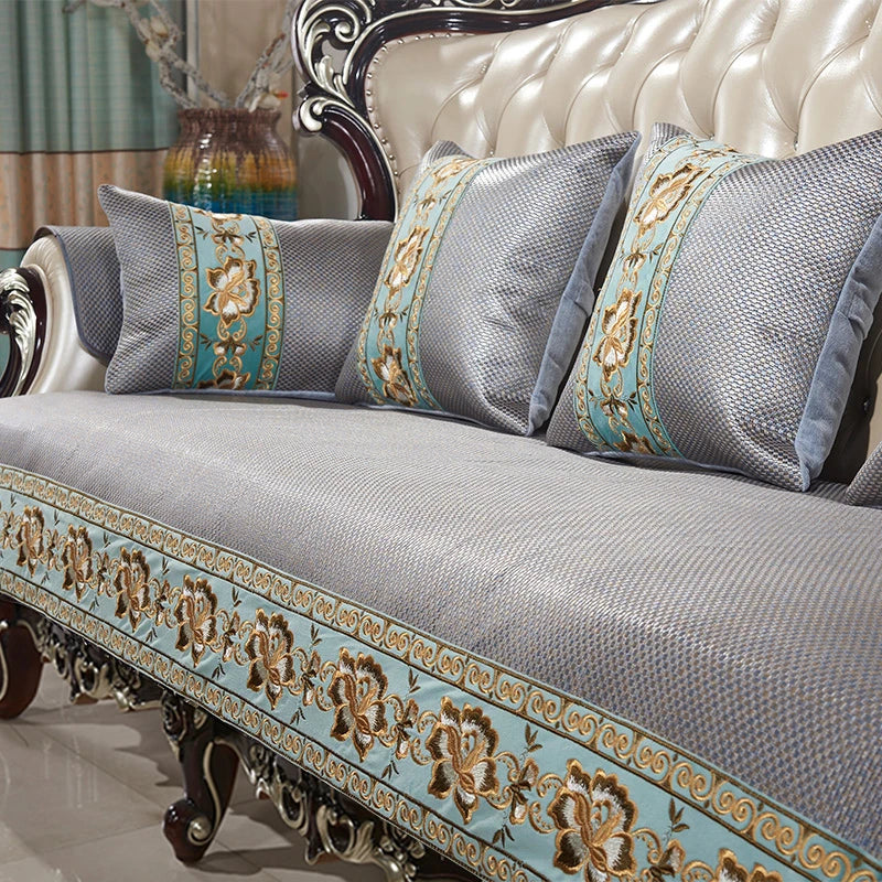 Un canapé élégant au design baroque, avec des motifs floraux dorés et des coussins gris décoratifs, offrant un style sophistiqué et luxueux à l'ameublement.
