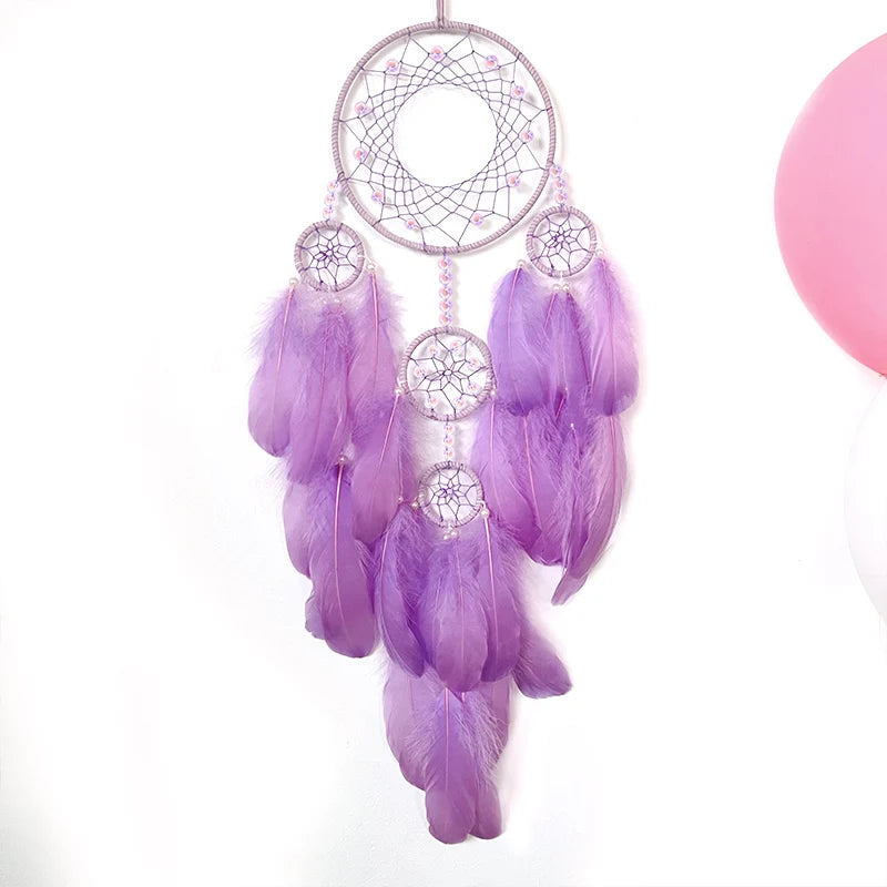 Un magnifique attrape-rêves violet suspendu avec des plumes délicates et légères, des anneaux tissés et des motifs en spirale, créant une décoration apaisante et mystique.