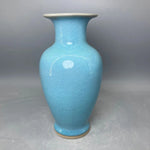 Un vase en céramique de couleur bleu turquoise avec un col distinct et une surface texturée.