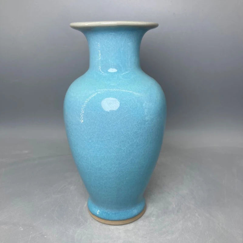 Un vase en céramique de couleur bleu turquoise avec un col distinct et une surface texturée.
