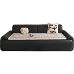 Canapé moderne en cuir noir avec des coussins décoratifs et un quilting en tissu crème.