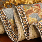 Un textile gris et doré, orné de motifs et de bordures décoratifs, évoquant une élégance et une richesse de style.