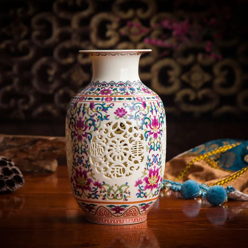 Vase en porcelaine décoré de motifs floraux, avec une ouverture ajourée et un design élégant posé sur une table en bois.