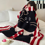 Une couverture moelleuse et rayée de rouge et de noir, avec un motif de chat mignon, offre un confort douillet sur le lit.
