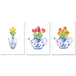Des bouquets de tulipes multicolores dans des théières en porcelaine ornées de motifs floraux bleus.