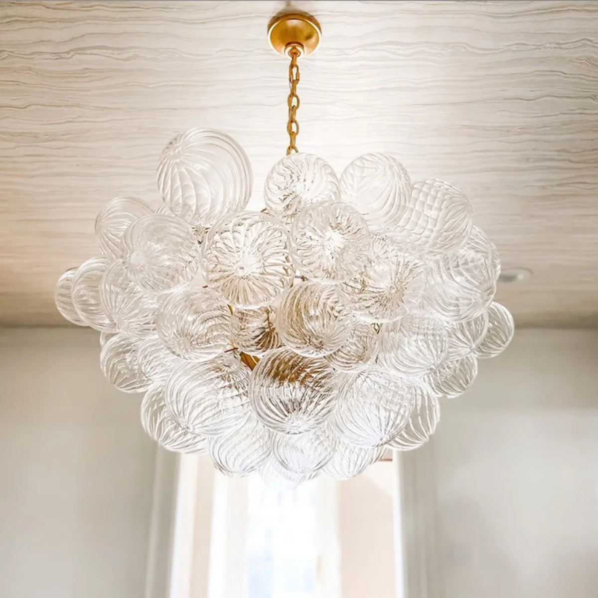 suspension lumineuse moderne verre transparent chaîne dorée led acier poli contemporain lumière chaude chambre