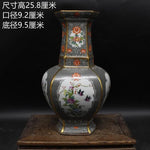 Vase décoratif de style ancien avec des motifs floraux colorés et des oiseaux sur un fond sombre.