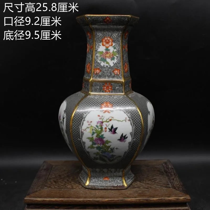 Vase décoratif de style ancien avec des motifs floraux colorés et des oiseaux sur un fond sombre.
