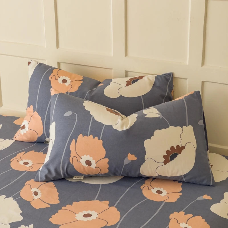 L'image montre des oreillers décoratifs avec un motif de fleurs stylisées dans des couleurs grises, blanches et orange pastel, créant un design élégant et apaisant.