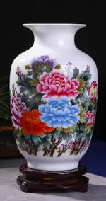 Un vase décoratif en porcelaine blanche aux motifs floraux multicolores, posé sur un support en bois.