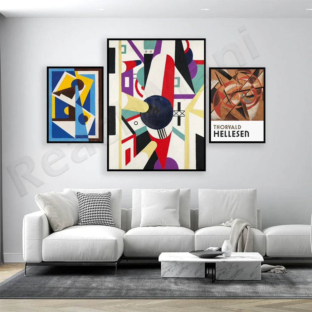 Cette image présente un ensemble de trois œuvres d'art abstraites encadrées, accrochées sur un mur blanc dans un salon moderne avec un canapé blanc et une table basse en marbre.