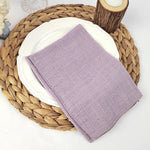 Un set de table en fibres tressées naturelles accueille une assiette blanche et un linge de table mauve.