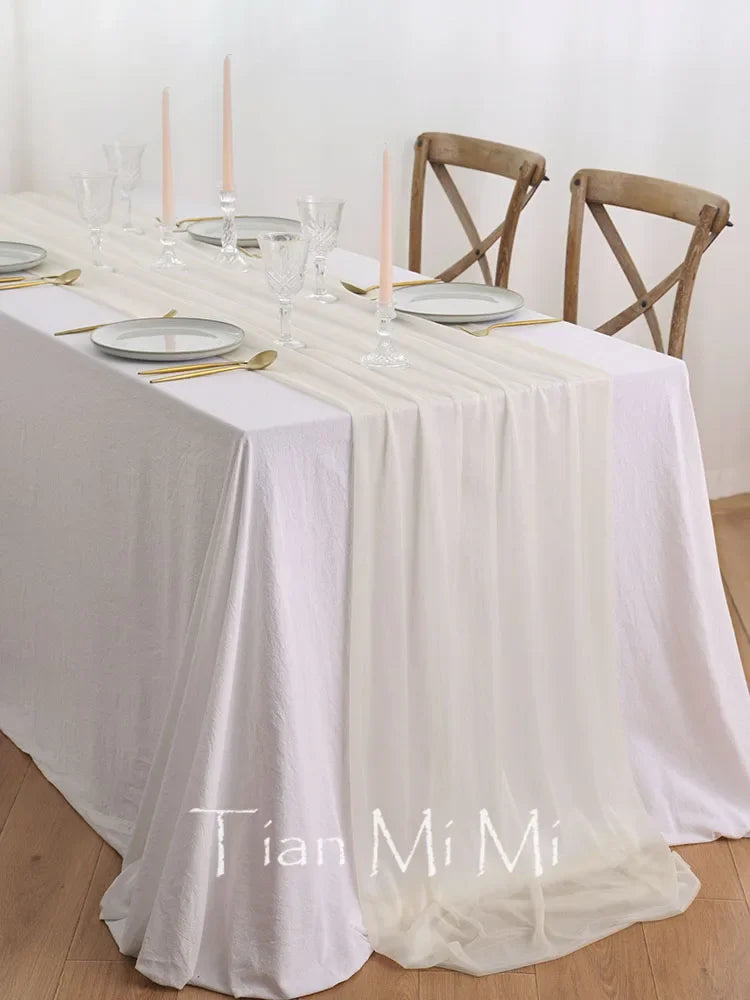 Table élégante avec nappe blanche, couverts dorés et chaises en bois.