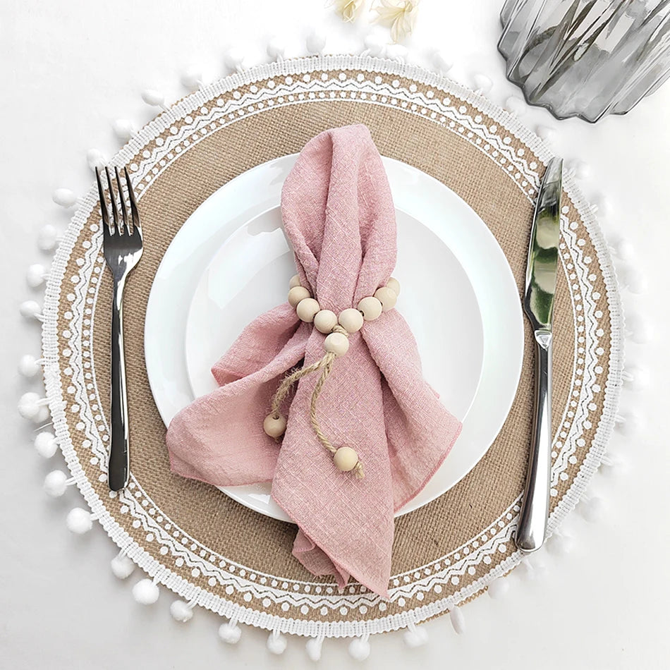 Magnifique décoration de table avec des accessoires en rose pastel et une belle nappe en coton ornée de pompons blancs, créant une atmosphère élégante et chaleureuse.