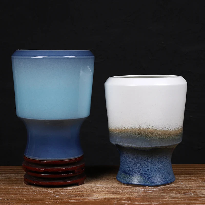 Deux vases en céramique de différentes formes et couleurs, posés sur une surface en bois, créent une scène harmonieuse et épurée.