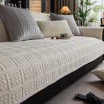 Un canapé gris matelassé avec des coussins assortis décore ce salon cosy, avec une plante verte ajoutant une touche de nature.