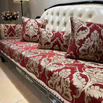 Le canapé élégant présente un motif floral baroque luxueux sur un riche fond rouge, créant une atmosphère sophistiquée et chaleureuse dans la pièce.