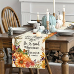 Sur la table de salle à manger, on peut voir une décoration automnale avec des citrouilles, des bougies allumées et un chemin de table avec un message biblique sur l'amour de Dieu qui dure pour toujours.