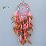 Rêve attrapeur en forme de cercle décoré de plumes roses, marron et blanches avec des perles roses, suspendu par un lien rouge.