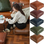 Pouf marocain gris clair utilisé comme repose-pieds près d'un canapé
